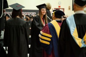 A recent graduate shakes hands with Dr. Lloyd Gestoso as she comes off the graduation stage.