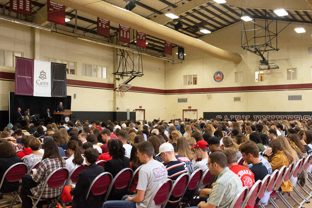 Students in MAC gymnasium listening to Dr. Williams speaking on stage
