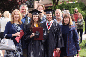 two graduates pose for photo with family members