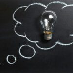 lightbulb on a chalkboard background. a thinking cloud is drawn around the lightbulb.