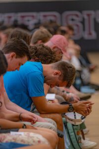 students with bowed heads in prayer at 2025 Convocation