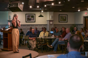 Charlotte Gleason standing on platform, presenting to a room of faculty